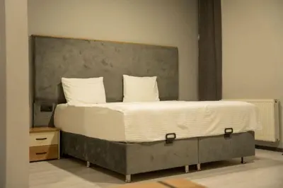 a bedroom with a large bed with a concrete headboard at Altınova Hotel Sakarya in Serdivan