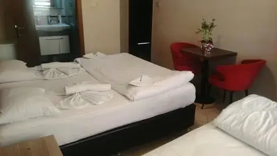 a room with two beds and a table and a red chair at Hotel Kiwi in Istanbul