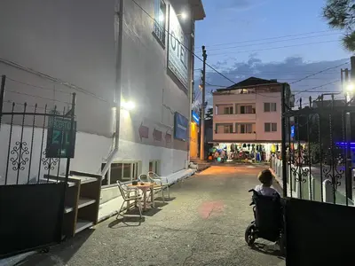 a woman in a wheelchair on a street at night at Kumbağ Otel in Kumbağ