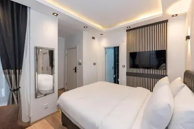 a white bedroom with a large bed and a television at Boutique 360 Suite in Istanbul