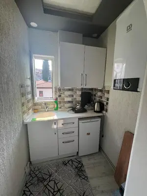 a small kitchen with white cabinets and a window at Suit 4 in Bursa