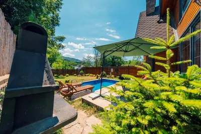 a backyard with a swimming pool and a green umbrella at Sapanca Grandwooden Deluxe in Sapanca