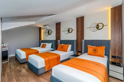 three beds in a room with orange and white at AirGate Airport Hotel in Arnavutköy