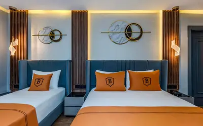 two beds with orange pillows in a room at AirGate Airport Hotel in Arnavutköy
