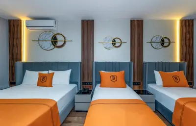 two beds with orange pillows in a room at AirGate Airport Hotel in Arnavutköy