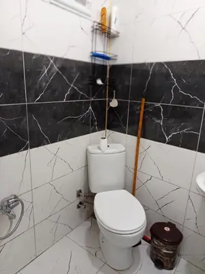a bathroom with a white toilet and black marble walls at Hilal Aparment Basement in Istanbul