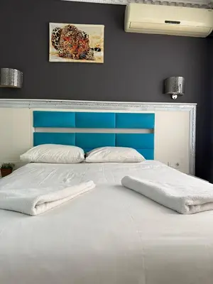 a large bed with a blue headboard and white sheets at Holiday Suit in Istanbul