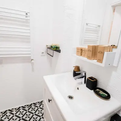 a white bathroom with a sink and a mirror at Modern apartment in the center of Kadıköy in Istanbul
