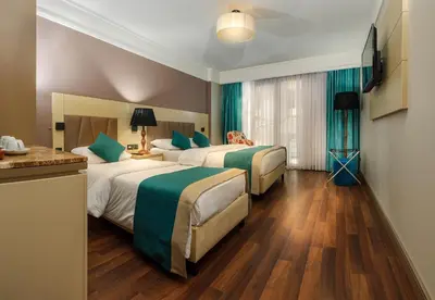 two beds in a hotel room with green curtains at Hotel Bossuite Kadikoy in Istanbul