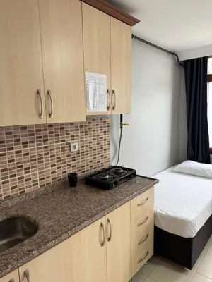 a kitchen with a sink and a bed in a room at Rumeli Pansiyon in Kumbağ