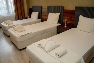a room with three beds with white pillows at Altuncu Premium Termal Hotel in Armutlu