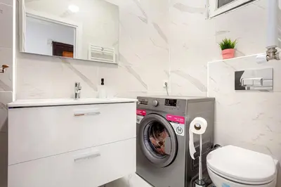 a white bathroom with a washing machine and a sink at Magnificent View Great Location in Istanbul