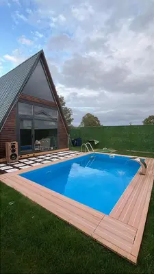 a large swimming pool on a deck next to a house at Shadeoffgreenbungalow
