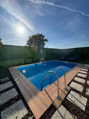 a swimming pool with a wooden deck and a fence at Shadeoffgreenbungalow