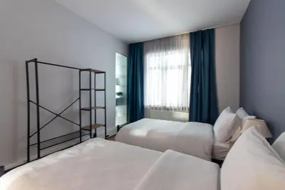 a hotel room with two beds and a window at Modern and Cozy 2BR in Vibrant Cihangir in Istanbul