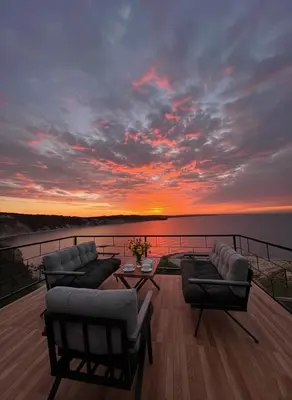 a deck with couches and a sunset on the water at Marina Boutique Hotel Istanbul Airport in Karaburun