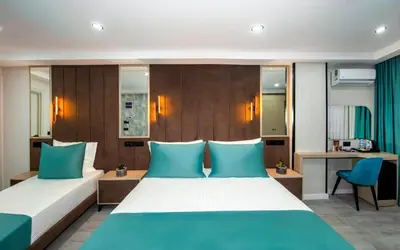 a hotel room with two beds and a desk at Cosinüs Airport Hotel in Arnavutköy