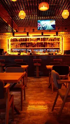 a restaurant with wooden tables and a bar with a tv at Tüm Palace Otel in Bandırma