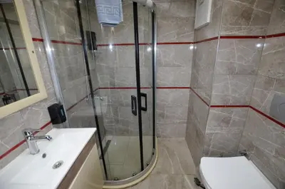 a bathroom with a shower and a toilet and a sink at Tüm Palace Otel in Bandırma