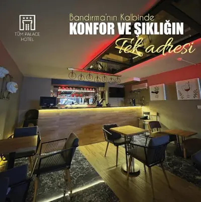 a restaurant with tables and chairs and a bar at Tüm Palace Otel in Bandırma