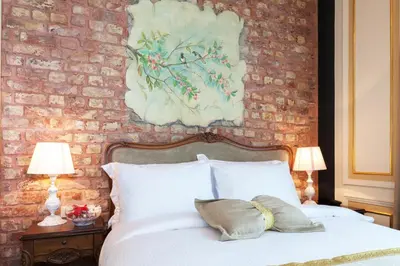 a bedroom with a white bed with a brick wall at Hotel Pera Parma in Istanbul