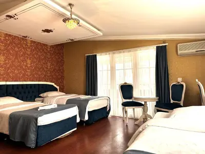 a hotel room with three beds and a table and chairs at Hotel Alyon Beyoğlu in Istanbul