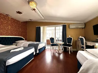 a hotel room with two beds and a table and chairs at Hotel Alyon Beyoğlu in Istanbul
