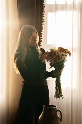 a woman holding a bouquet of flowers in front of a window at The Yard Hotel in Istanbul