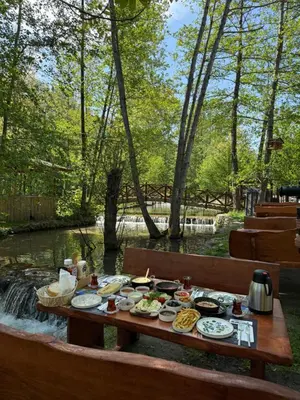 a picnic table with food on it next to a river at HARA Bıçkıdere in Akyazı