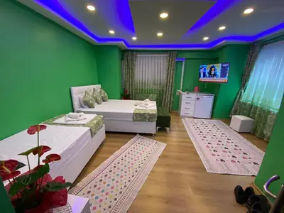 a green room with two beds and a tv at Işıl Otel Old City in Istanbul