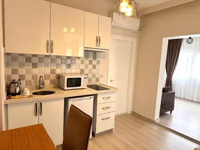 a kitchen with white cabinets and a microwave and a table at Şeker Apartments in Tuzla