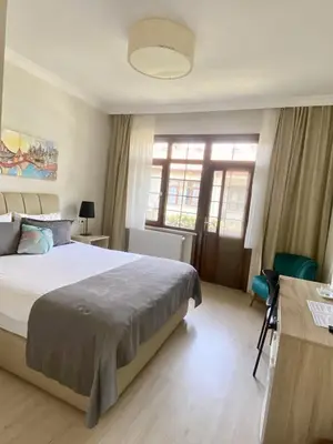 a bedroom with a bed and a desk and windows at Kerpe Diem Otel in Kerpe