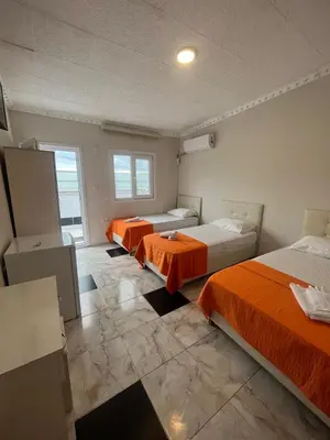 two beds in a room with orange sheets at Grand Şakar Otel in Marmara