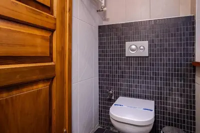 a bathroom with a toilet and a black tiled wall at Cool Authentic 2BD2Bath Galata Tower Home! #413 in Istanbul