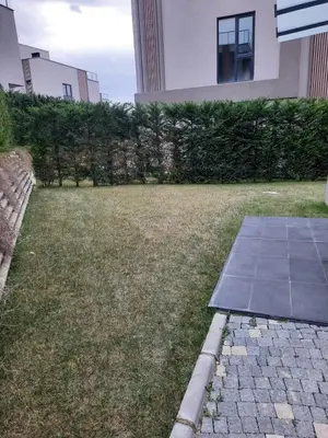 a lawn in front of a house with a tiled sidewalk at Villa with private pool for daily rent in Istanbul in Buyukcekmece