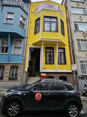 a black car parked in front of a yellow house at SARIKÖŞK HOTEL Kadıköy in Istanbul