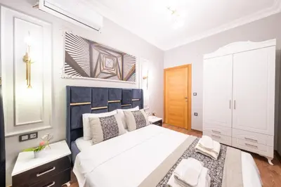 a bedroom with a large white bed with a blue headboard at King Suit Beşiktaş apart in Istanbul