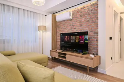 a living room with a tv and a brick wall at BSY's Stylish 1BR,2BR ,3BR Apartments in Brand New Building in Istanbul