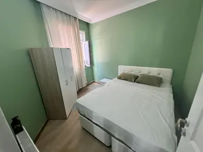 a small bedroom with a white bed and green walls at Meryy Home in Istanbul