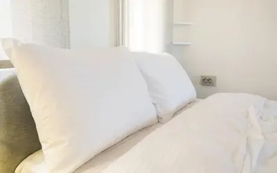 a bed with white sheets and pillows next to a window at Hill House Hostel in Istanbul