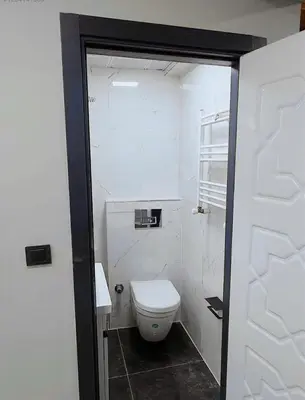 a white bathroom with a toilet and a door at Innova Suit Hotel in Istanbul