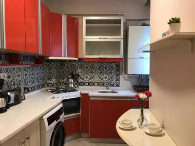 a kitchen with red cabinets and a vase of flowers on a table at Apartment on Pier Loti street with a nice view in Istanbul