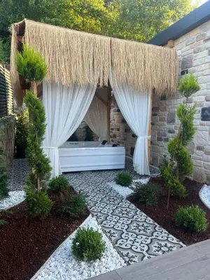 a garden with a bed and a straw umbrella at Rubyy Resort Luxury Stone Villa with Private Pool in Kartepe