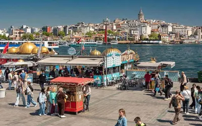 a group of people walking on a pier near the water at otel efendi in Istanbul