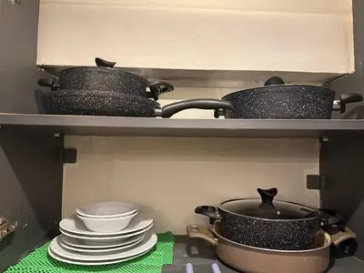a shelf with pots and pans and plates in a kitchen at Cozy 1BR Basement Apartment Close to Metro in Istanbul