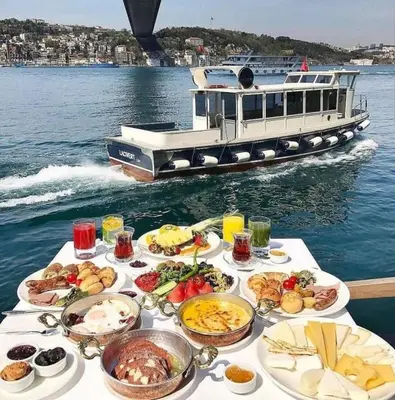 a table with many plates of food and a boat at 2BR Modern Flat in Nişantaşı 3 Min to Metro Full AC in Istanbul