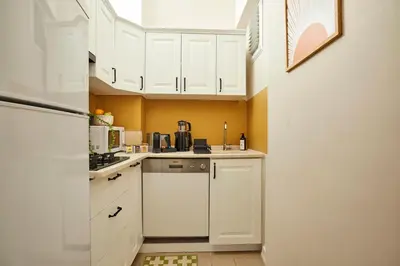 a small kitchen with white cabinets and a refrigerator at Prime Nişantaşı 2BR Flat 3-Min Walk to Metro in Istanbul