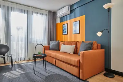 an orange couch in a living room with a blue wall at Superb Location 3 Min to Metro AC Elevator in Istanbul