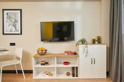 a living room with a white cabinet and a tv on a wall at Heart of the City 3 Min to Metro 2BR AC in Istanbul