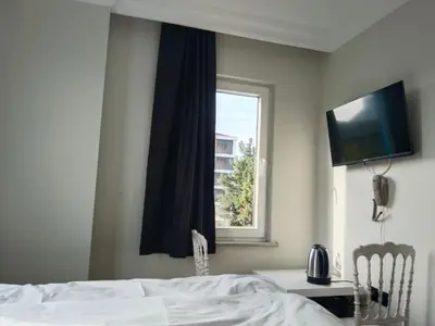 a bedroom with a bed and a window with a television at White garden in Tuzla